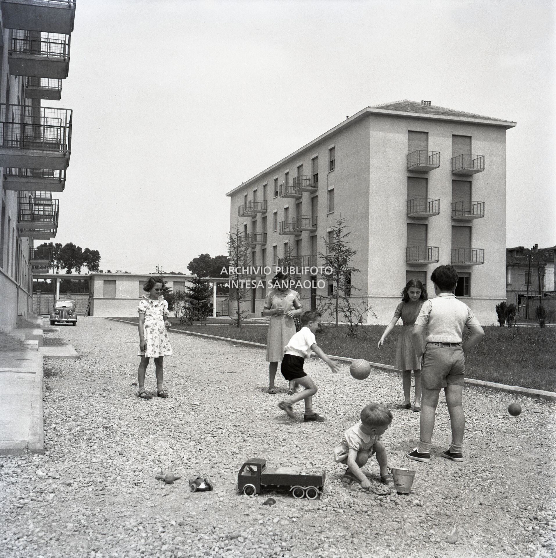 Children playing in courtyards of houses inhabited by Montecatini factory workers in the Affori district of Milan
