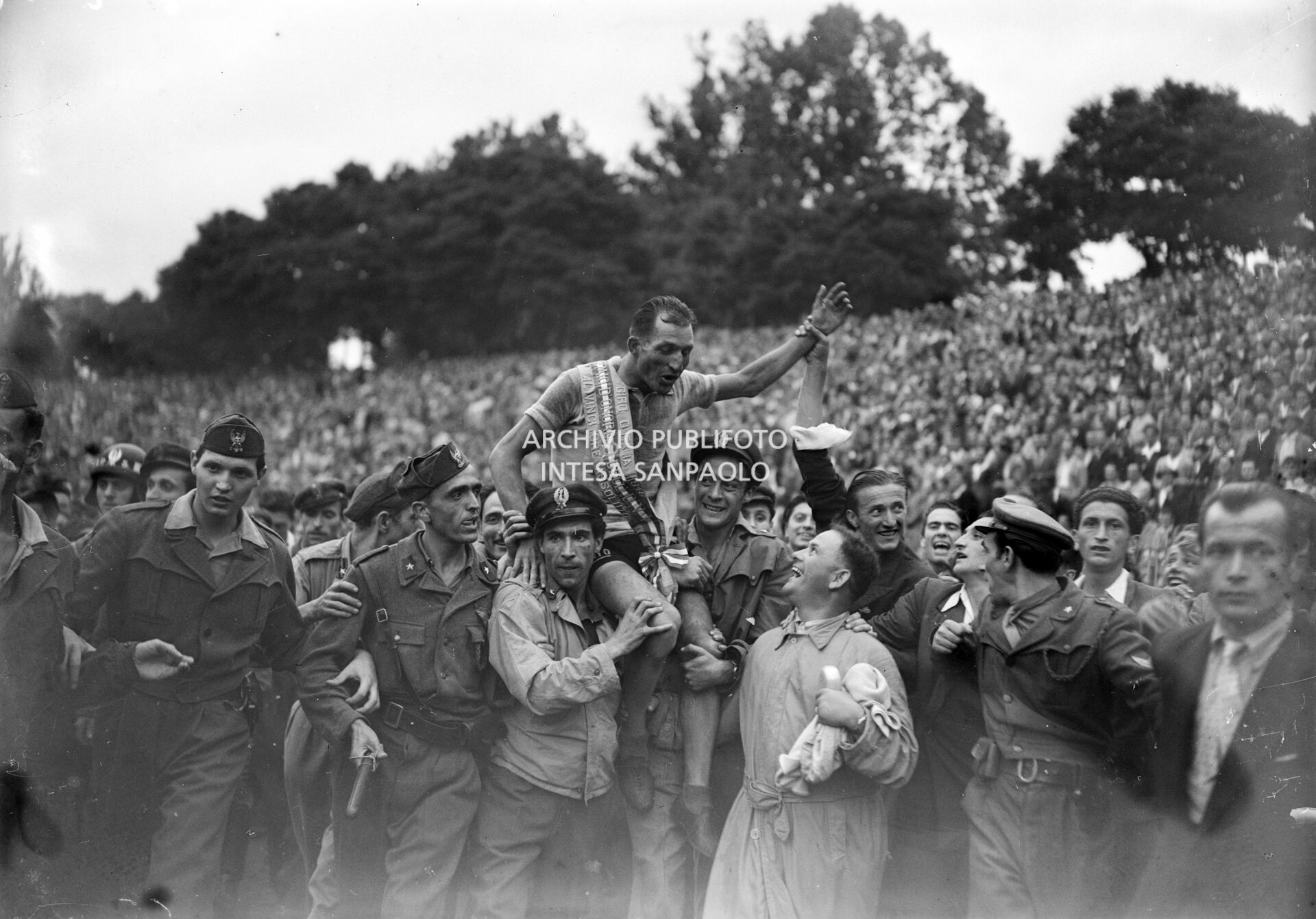 Gino Bartali carried triumphantly by fans at the Arena of Milan where he has just finished the 29° Giro d'Italia