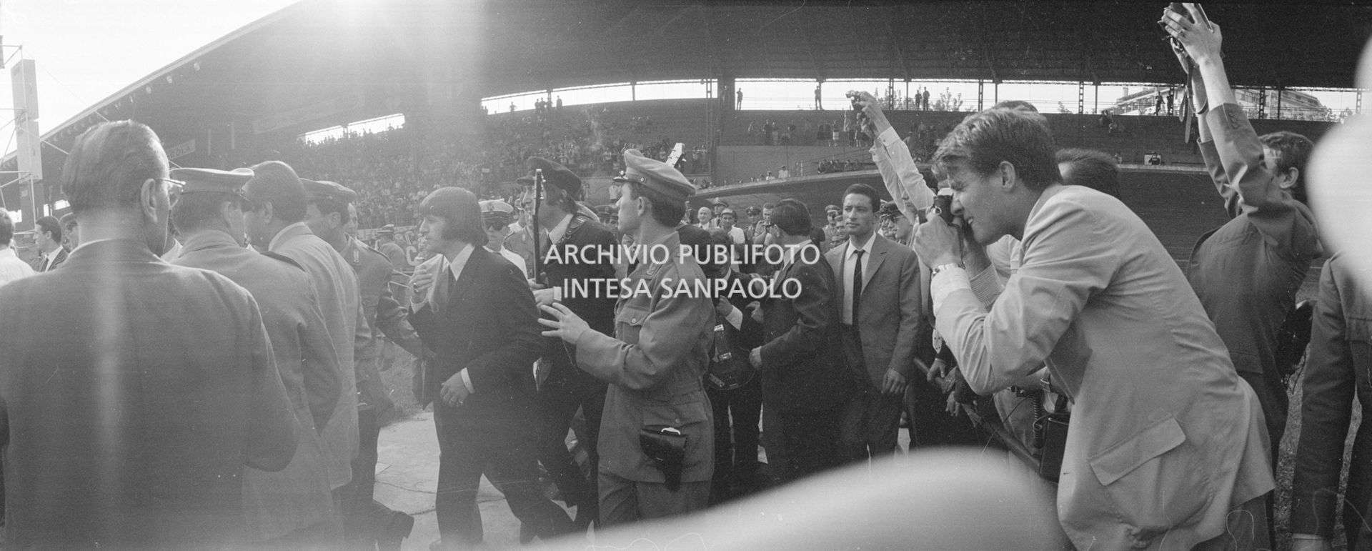 I Beatles, scortati dalle forze dell'ordine, fanno il loro ingresso al Vigorelli di Milano, 24 june 1965, Cossu, Sergio, Pavone, Eugenio, Publifoto