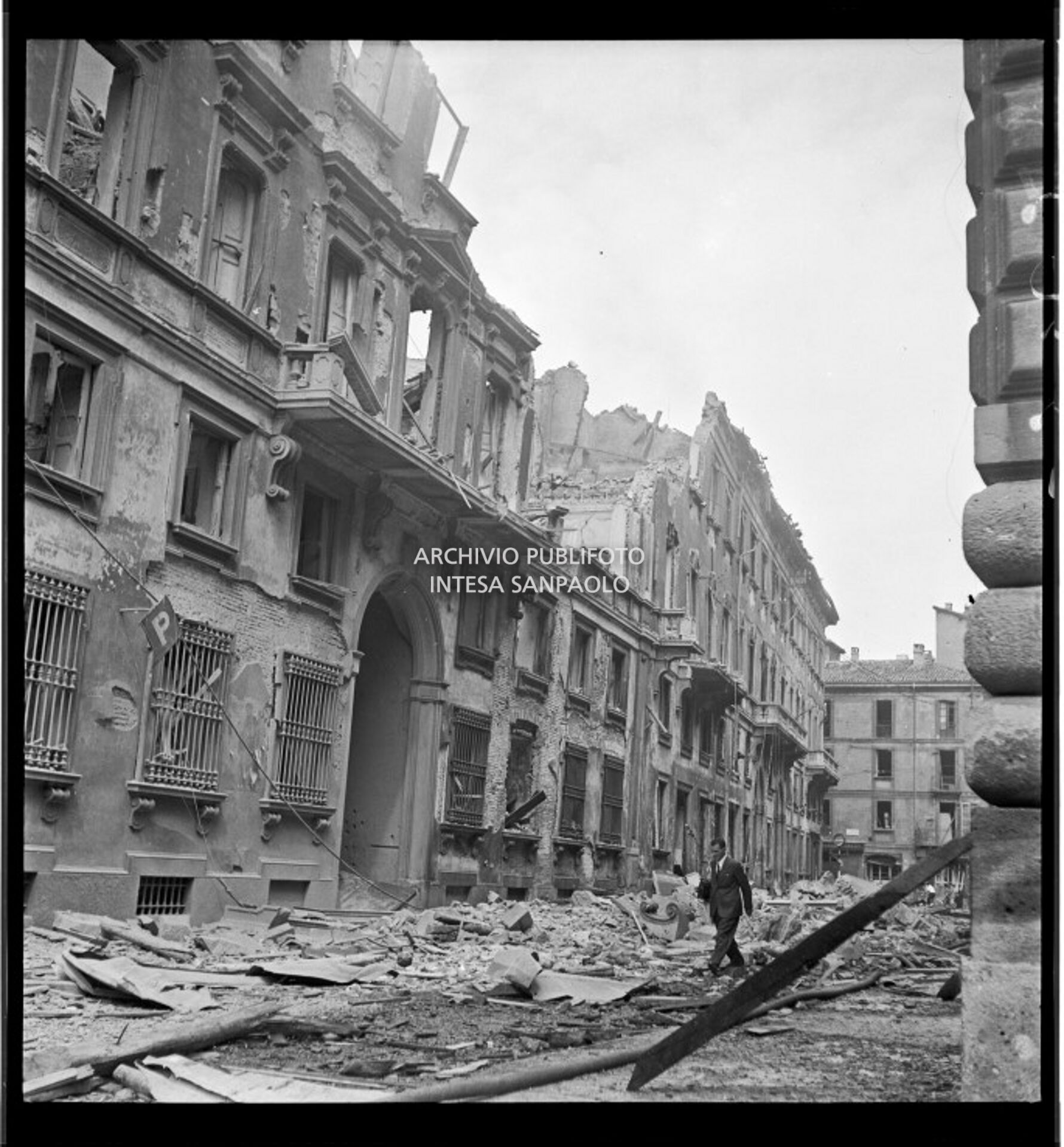 Un uomo cammina in via Brera, a Milano, tra le macerie dei palazzi bombardati