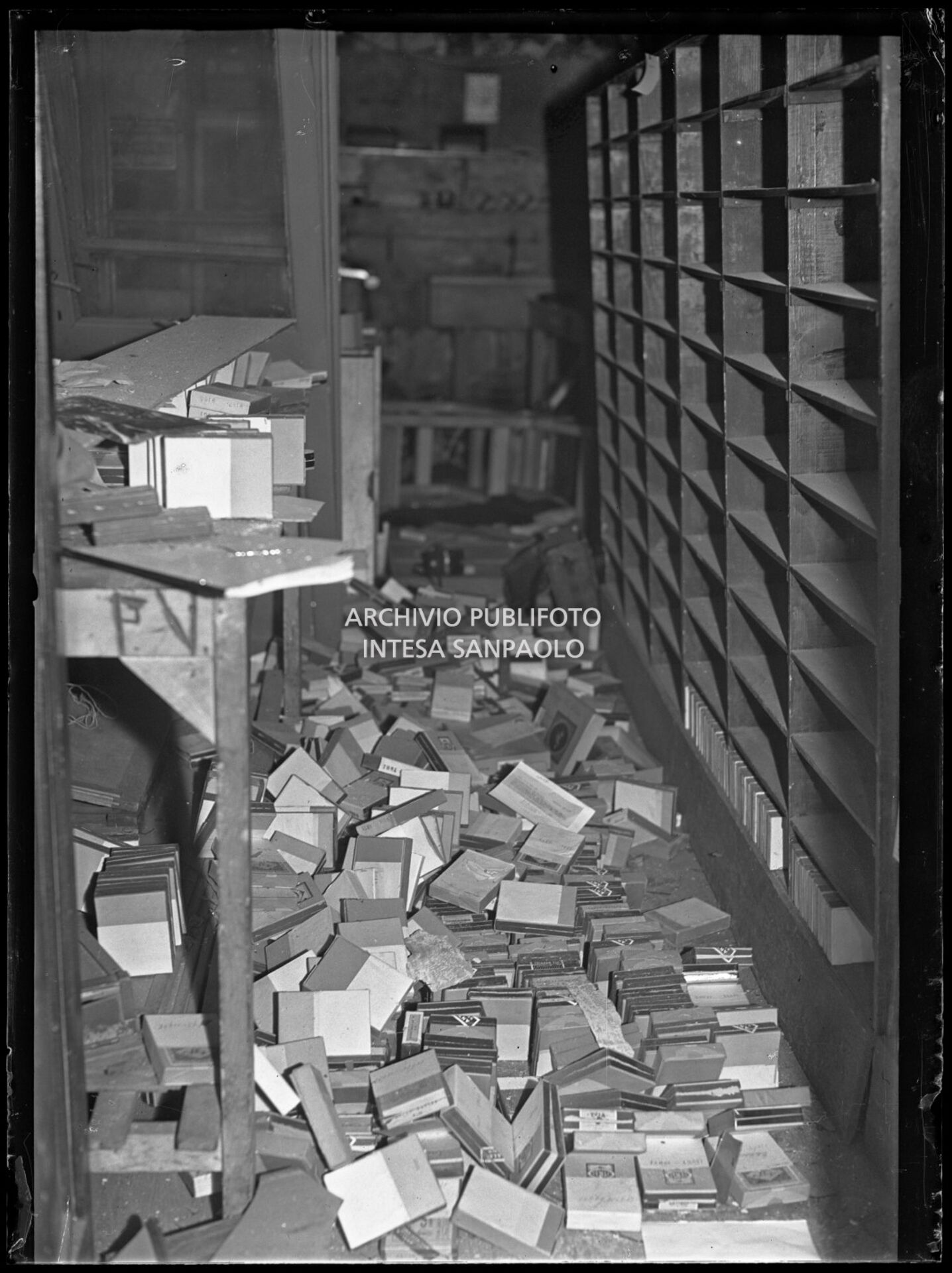 Interno dell'archivio dell'agenzia Publifoto in via Solferino 36, a Milano, dopo i bombardamenti: a terra le scatole con i negativi