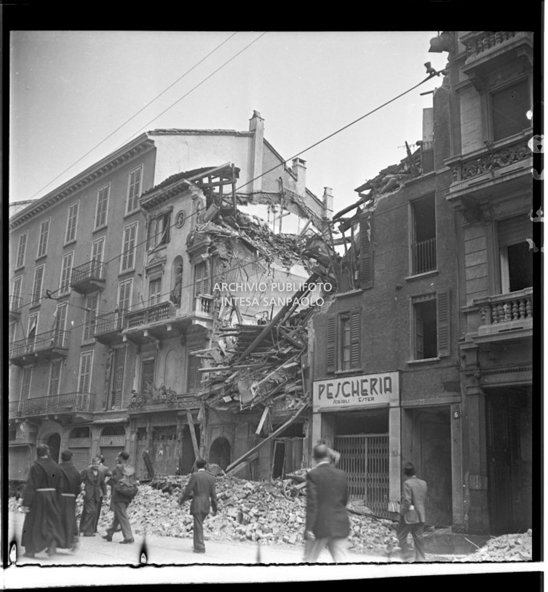 Passanti osservano l'edificio in via Ponte Vetero 8 a Milano distrutto dai bombardamenti; al civico 6 la pescheria di Ester Scajoli