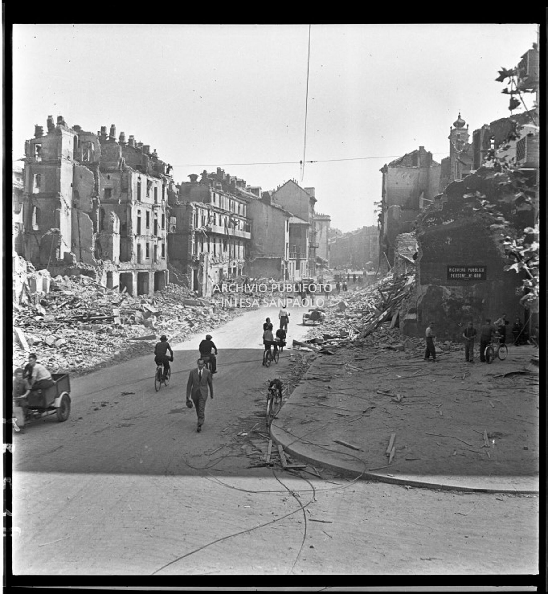 Veduta di via Molino delle Armi a Milano con gli edifici distrutti dai bombardamenti. Le macerie sono state addossate ai lati della strada per consentire la circolazione di biciclette, pedoni, carretti come quelli visibili nell'immagine