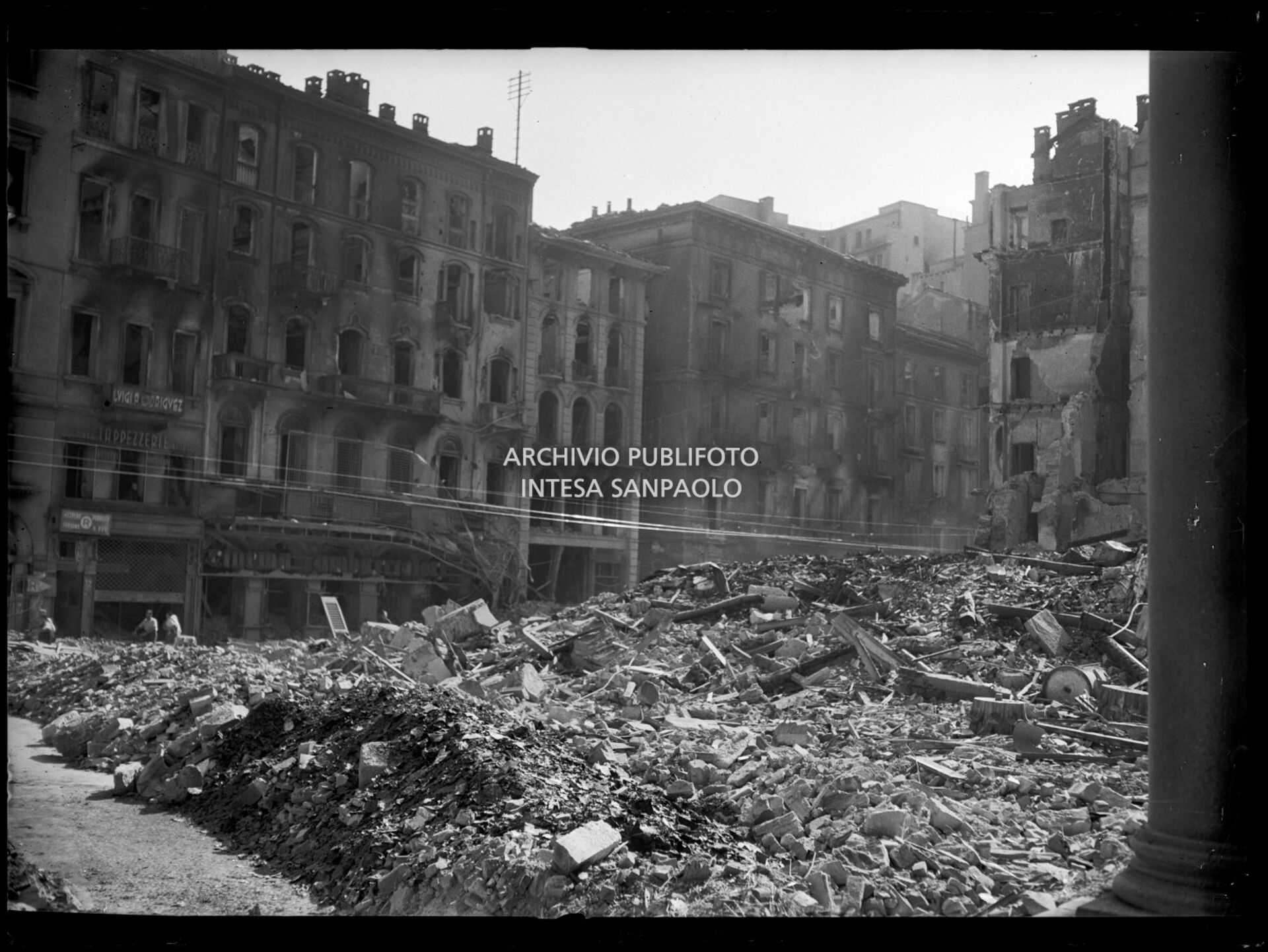 Gli edifici che si affacciano su corso Vittorio Emanuele II a Milano sventrati dai bombardamenti tra cui il cinema Ambasciatori. Piazza San Carlo è completamente ingombra di macerie