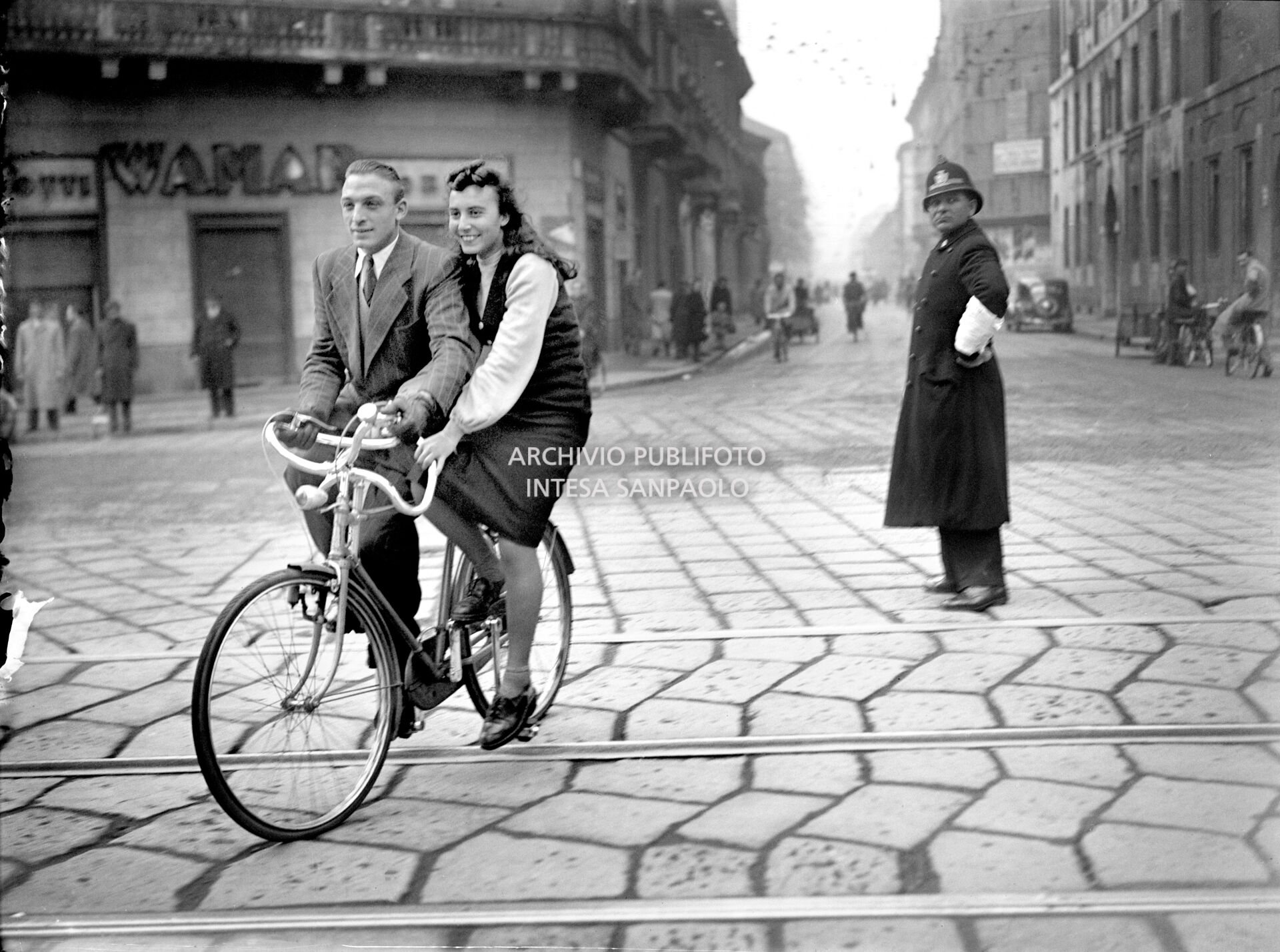 A man and woman on a special bicycle with two parallel seats in Milan