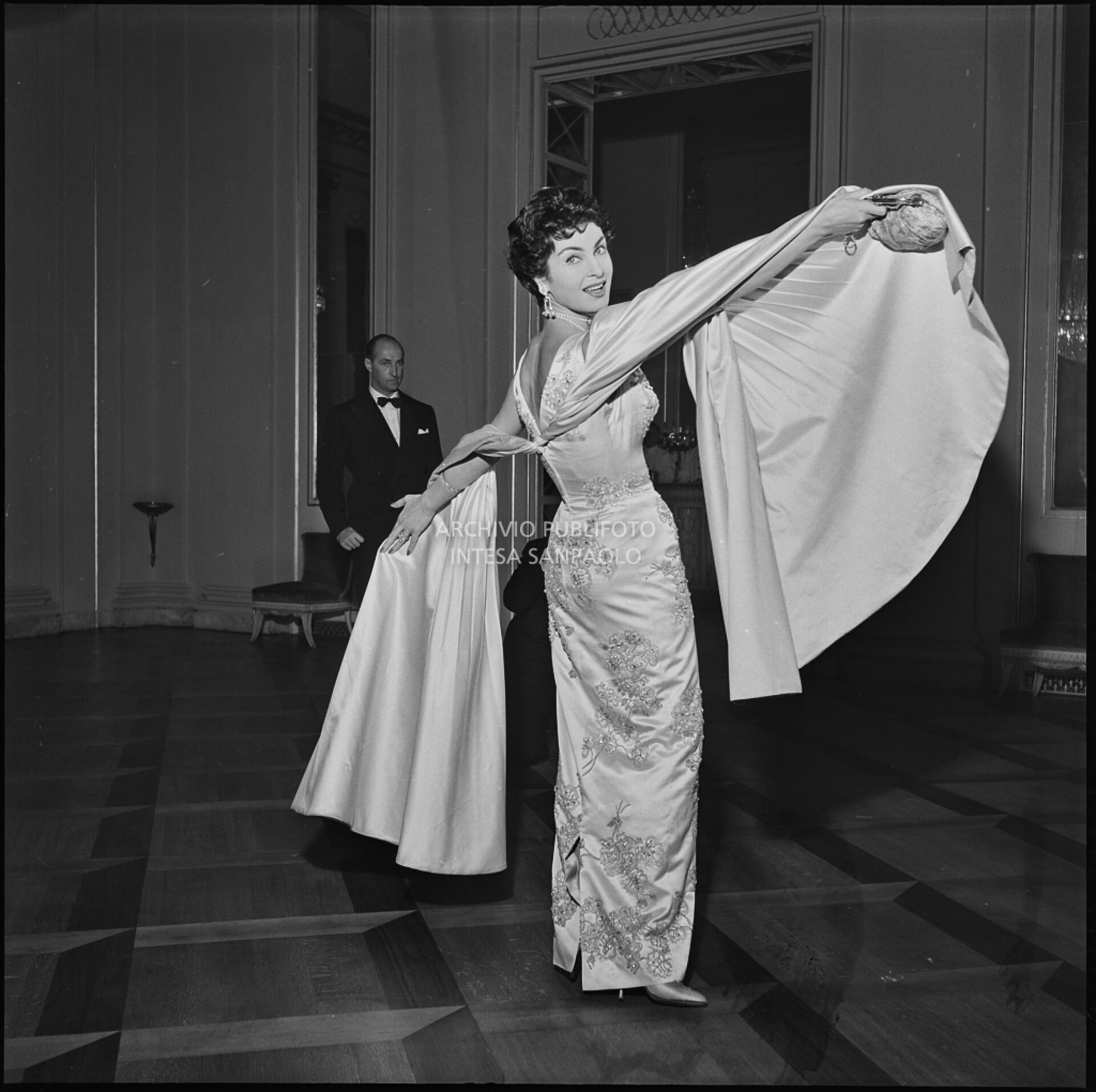 Silvana Pampanini esibisce il proprio abito da sera, al Teatro alla Scala, in occasione della serata inaugurale della stagione lirica 1956-1957 con l'opera "Aida" di Giuseppe Verdi, diretta da Antonino Votto, con la regia di Franco Enriquez
