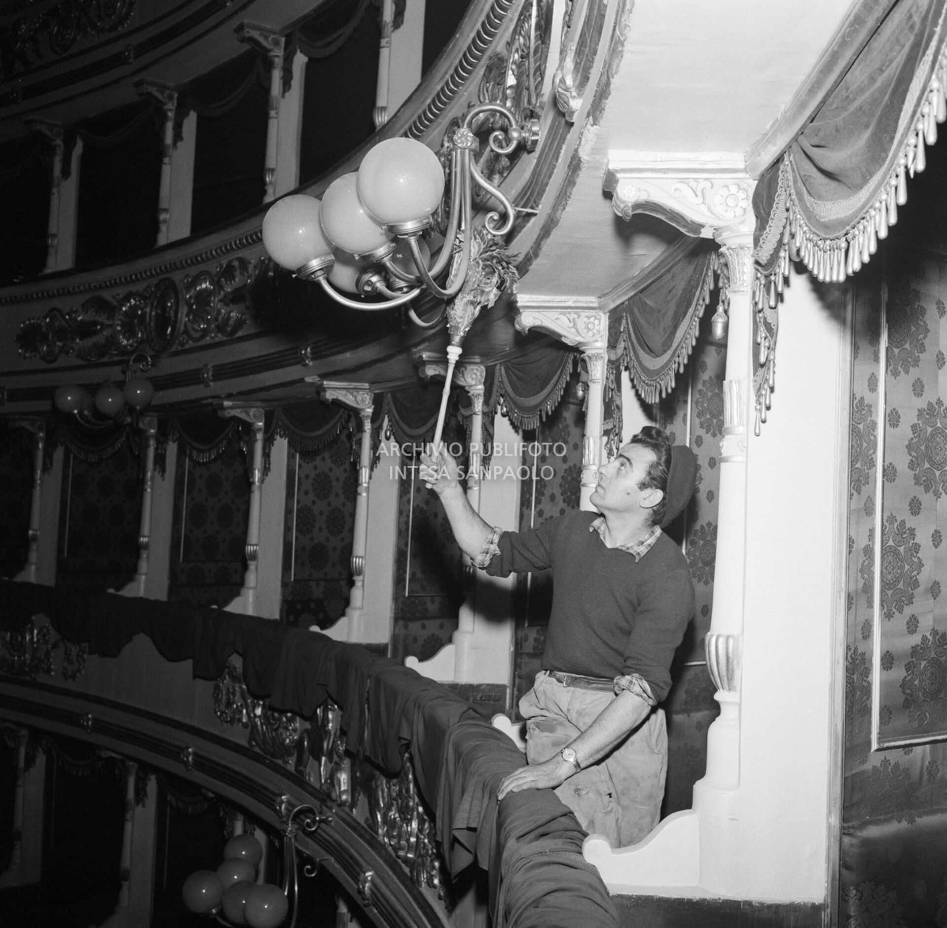 Addetto alle pulizie spolvera un lampioncino dei palchi  in vista dell'inaugurazione della stagione lirica 1957-1958 del Teatro alla Scala
