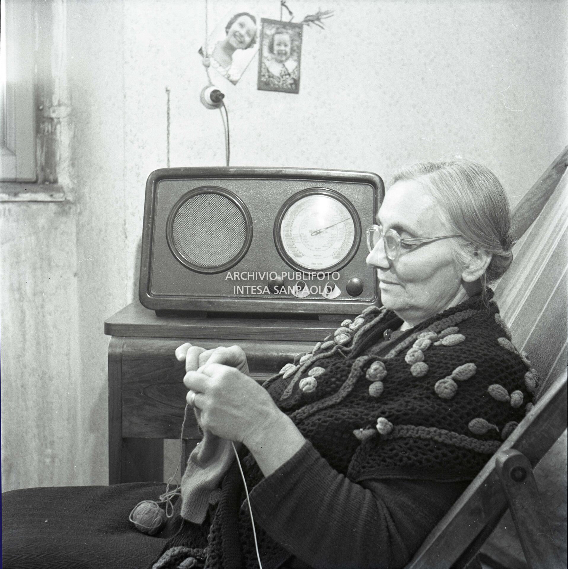 An old woman knits while listening to the radio
