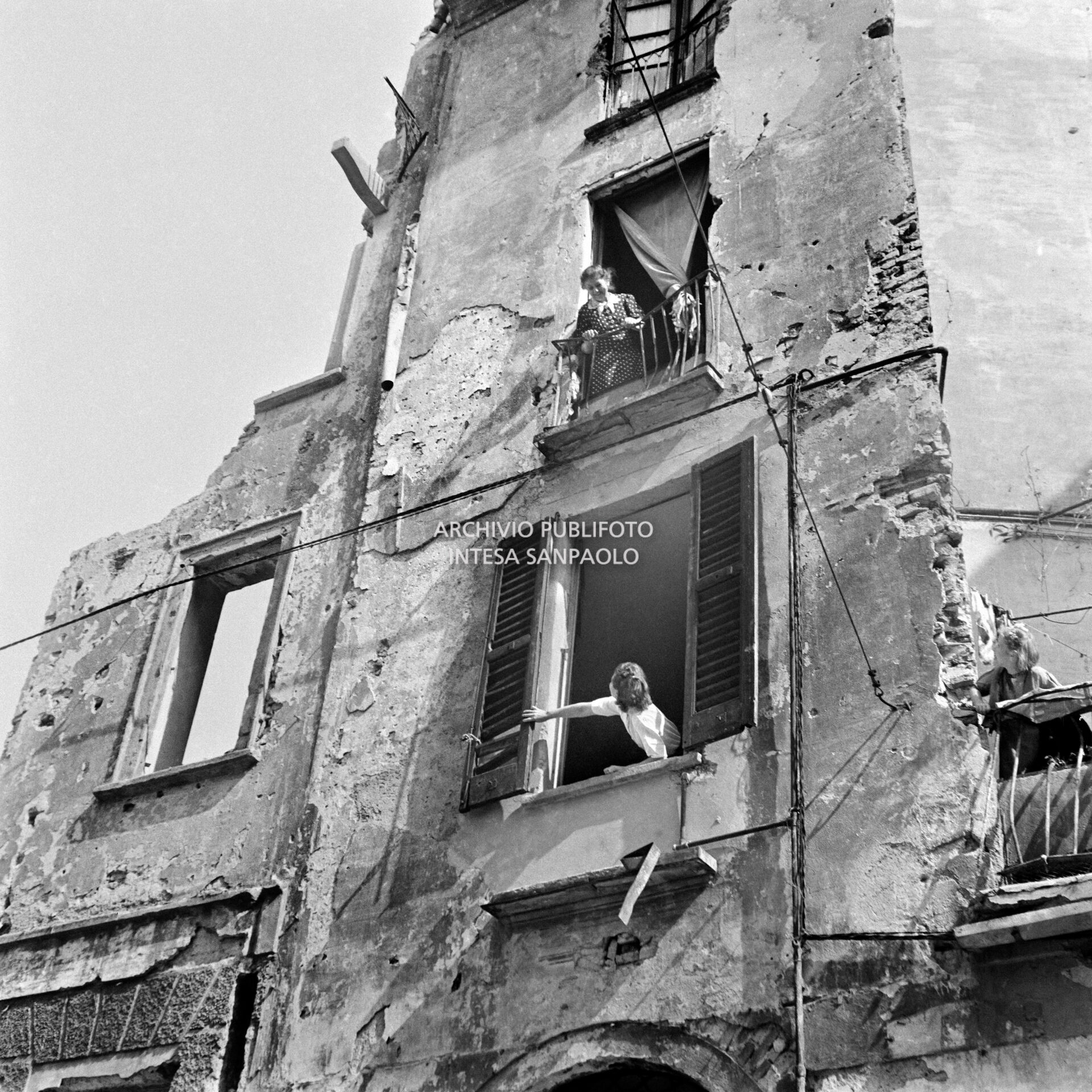 Women chatting in front of bomb-shelled houses in Milan