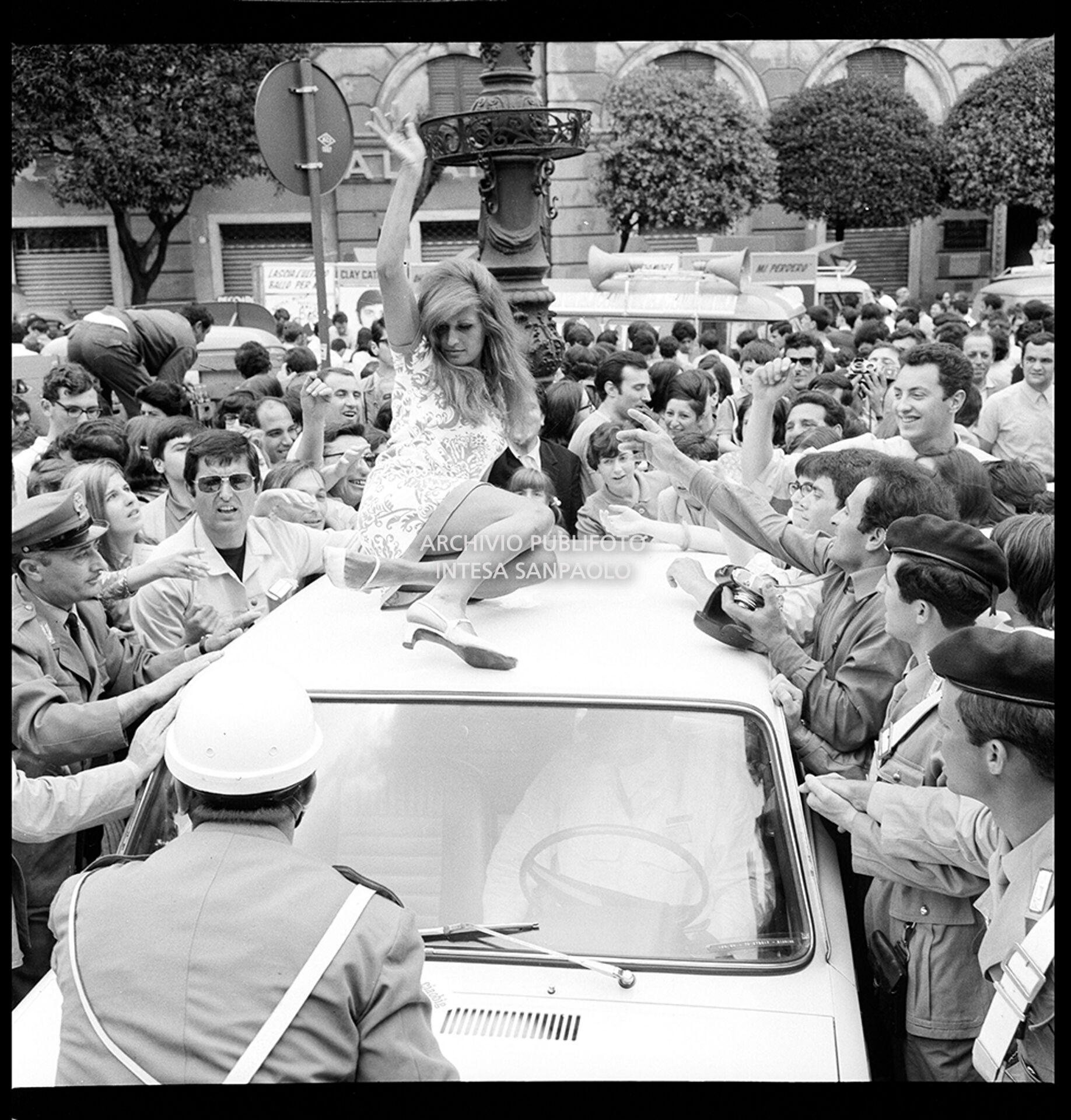 Dalida on the roof of a car, surrounded by fans during one stop of the 7° Cantagiro