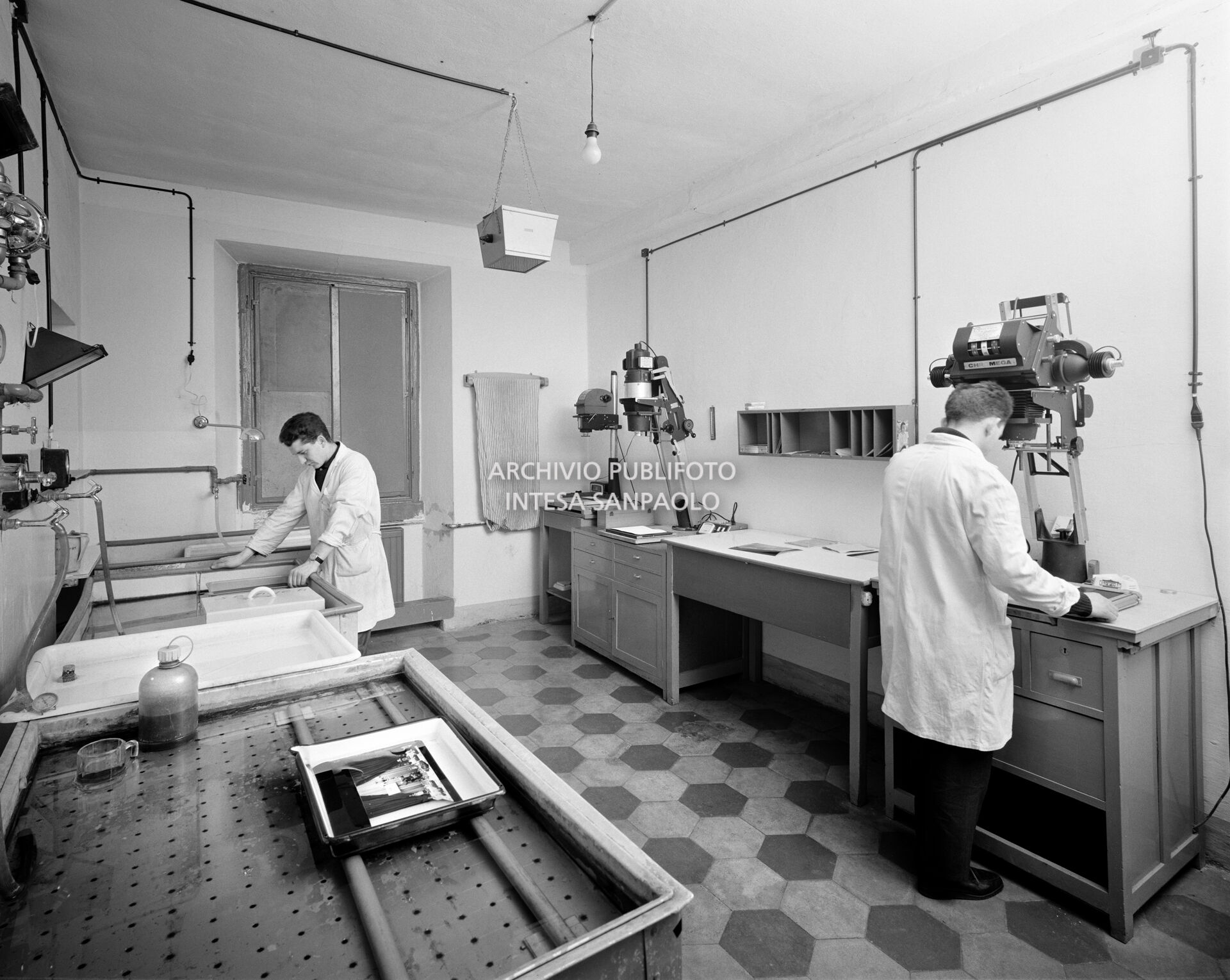 Addetti al lavoro nel laboratorio con camera oscura della sede dell'agenzia Publifoto in via Bramante a Milano