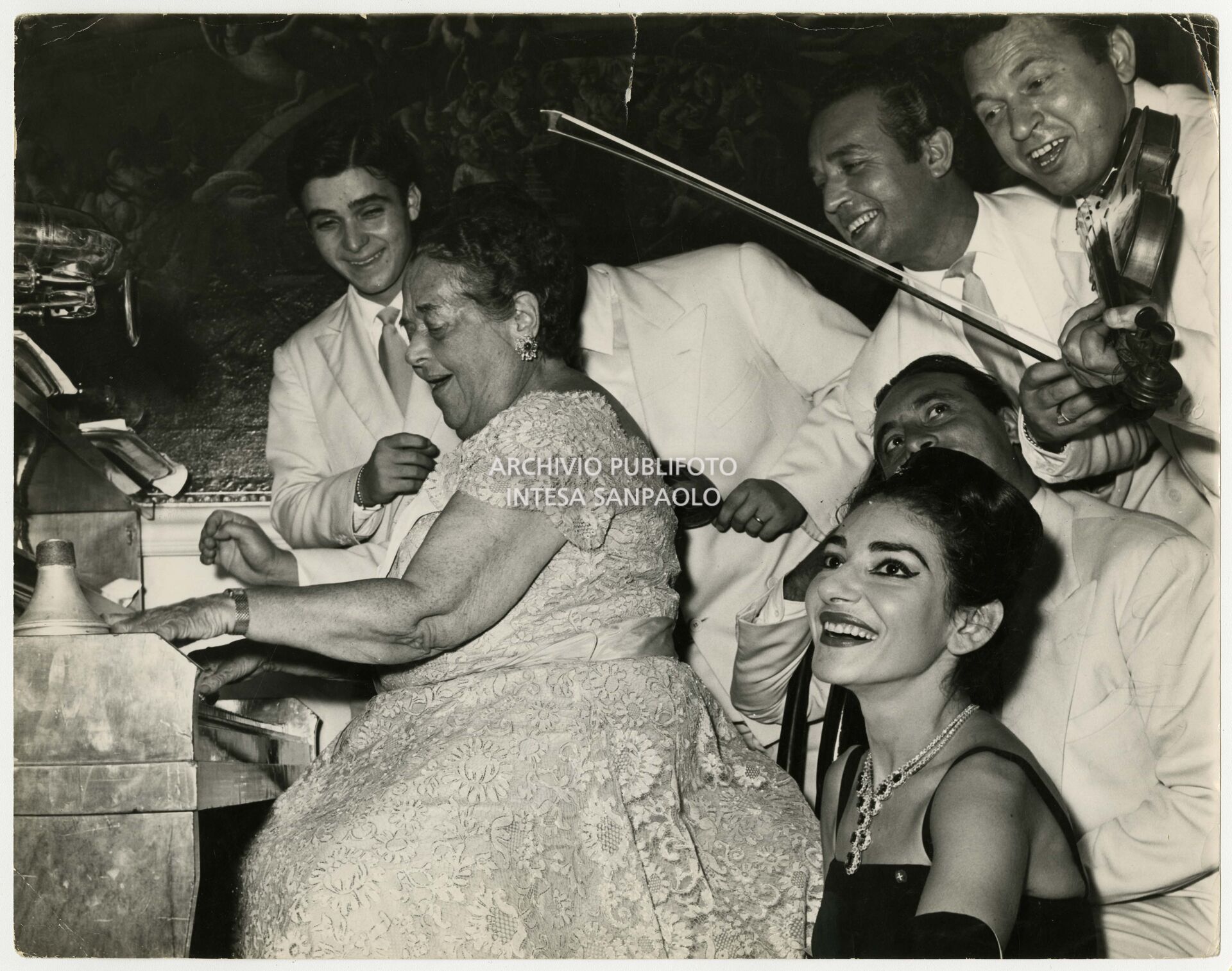 Maria Callas at the reception organised in her honour by Elsa Maxwell, pictured at the piano