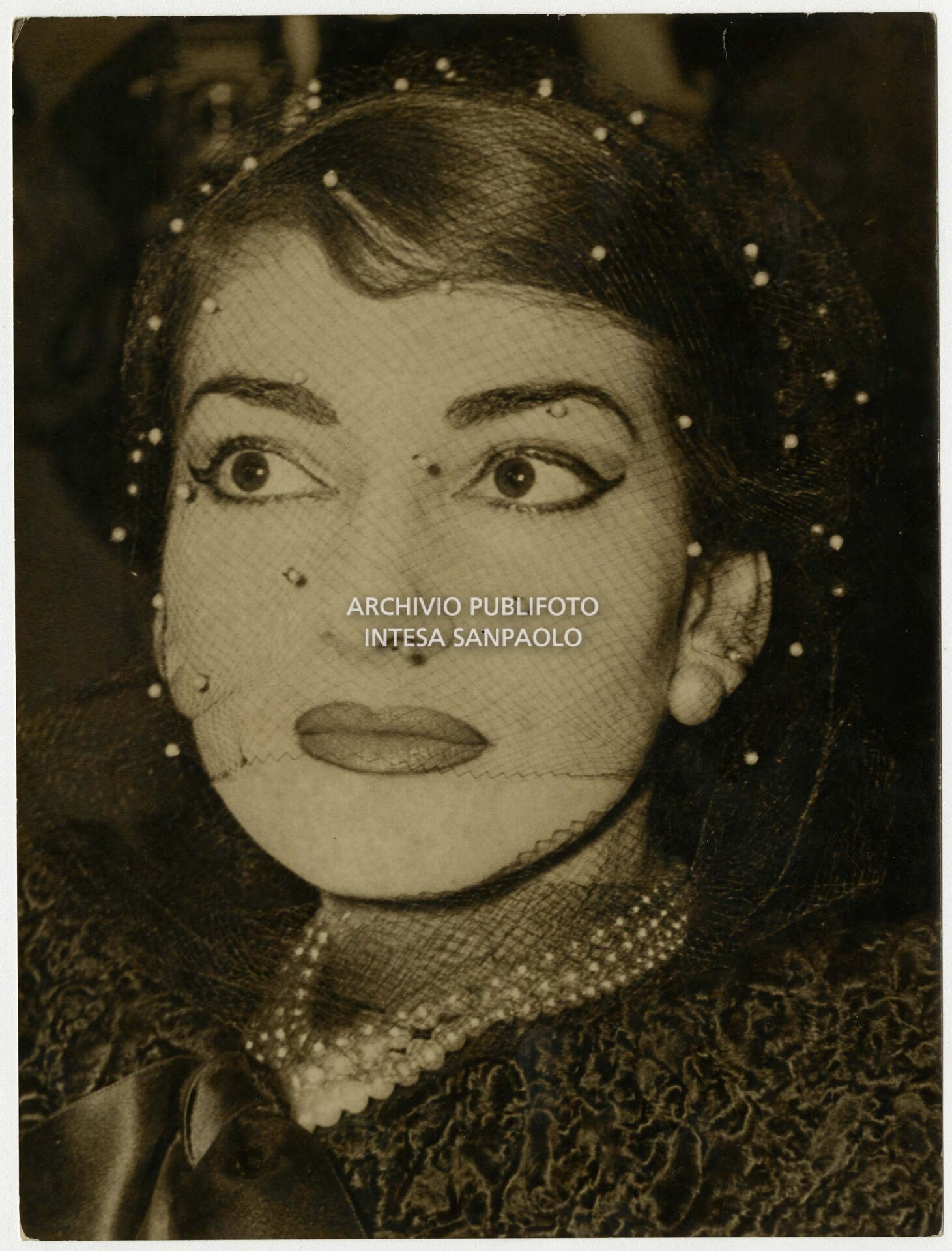 Maria Callas ritratta in occasione della conferenza stampa tenutasi qualche giorno dopo la serata inaugurale della stagione del Teatro dell'Opera di Roma; la soprano, che interpretava la Norma di Bellini, alla fine del primo atto si ritirò in camerino a causa di una brutta raucedine e non rientrò in scena