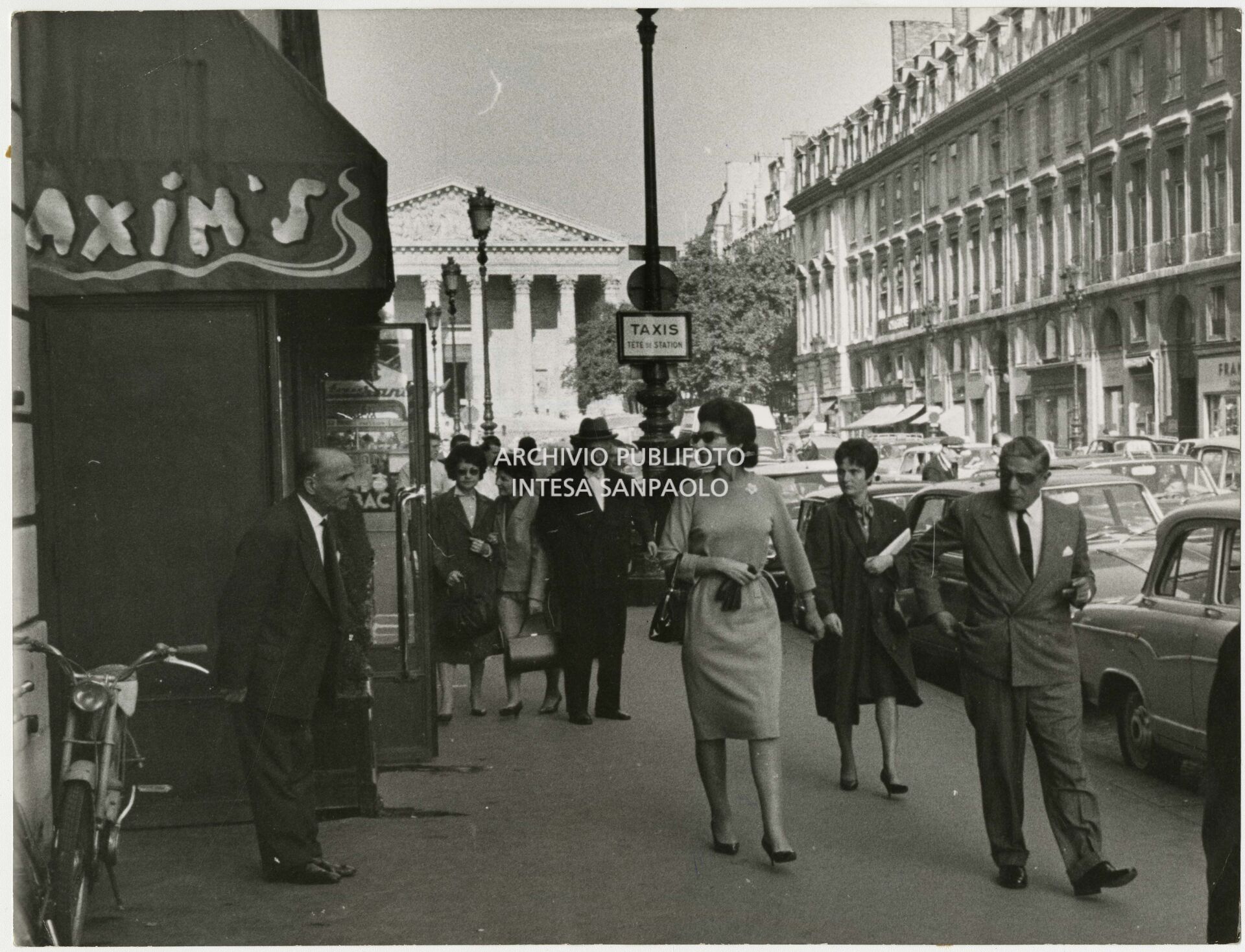 Maria Callas and Aristotele Onassis strolling along rue Royale outside "Chez Maxim's"