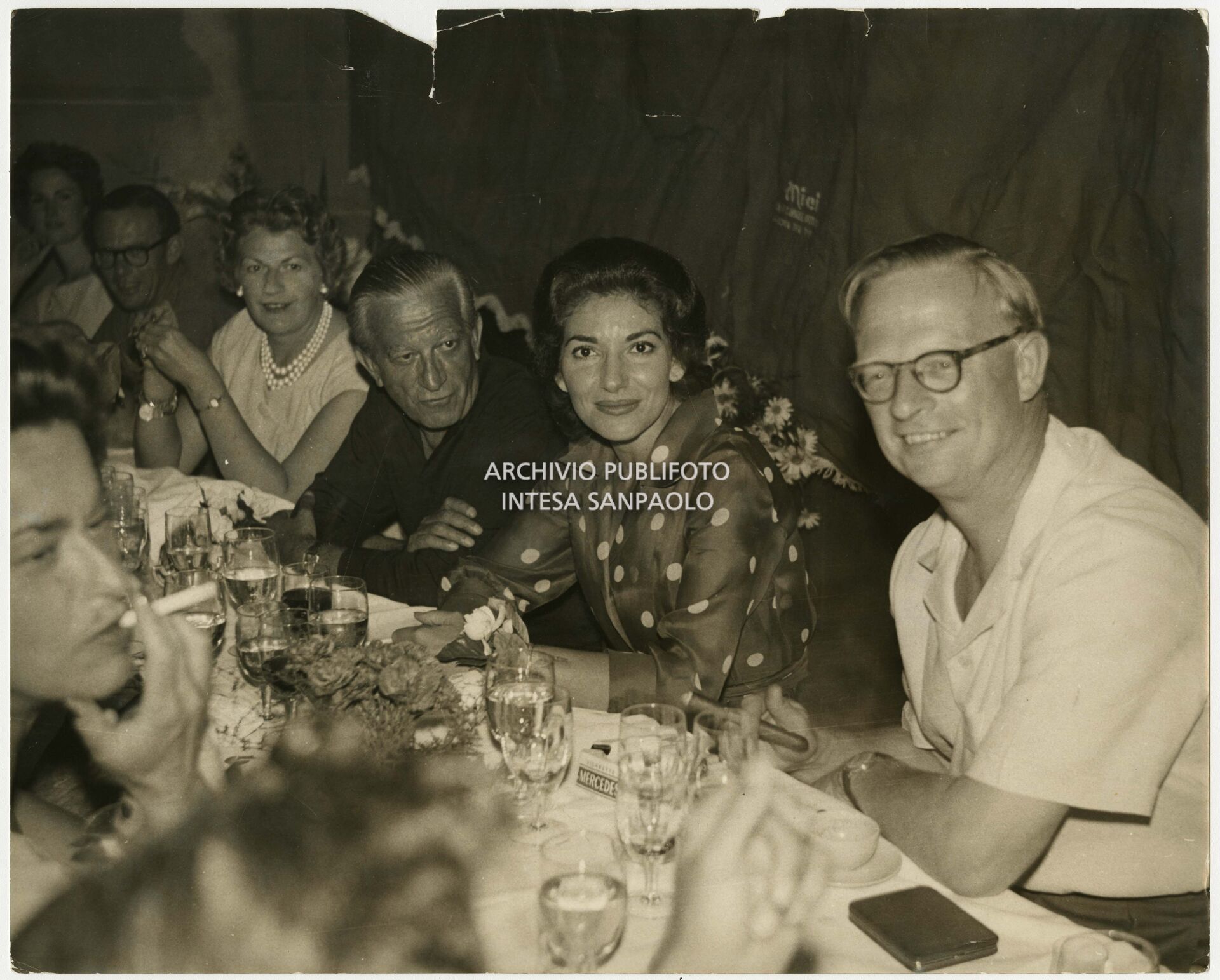 Maria Callas seduta a tavola al ristorante, alla sua destra Enrico Piaggio (terzo da destra) e alla sua sinistra John Ian Russell, XIII duca di Bedford