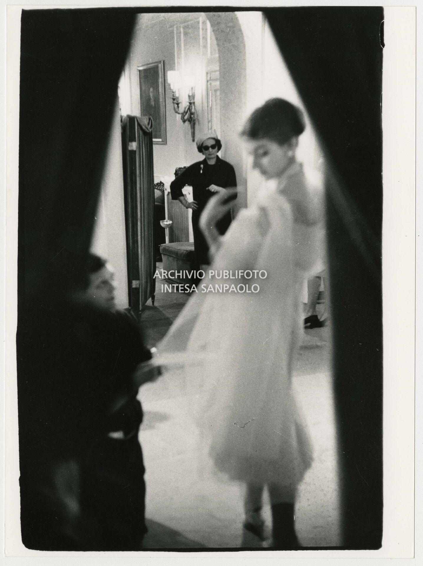 Maria Callas prova un abito nell'atelier Biki sotto lo sguardo della stilista Elvira Leonardi Bouyeure, detta Biki, sullo sfondo