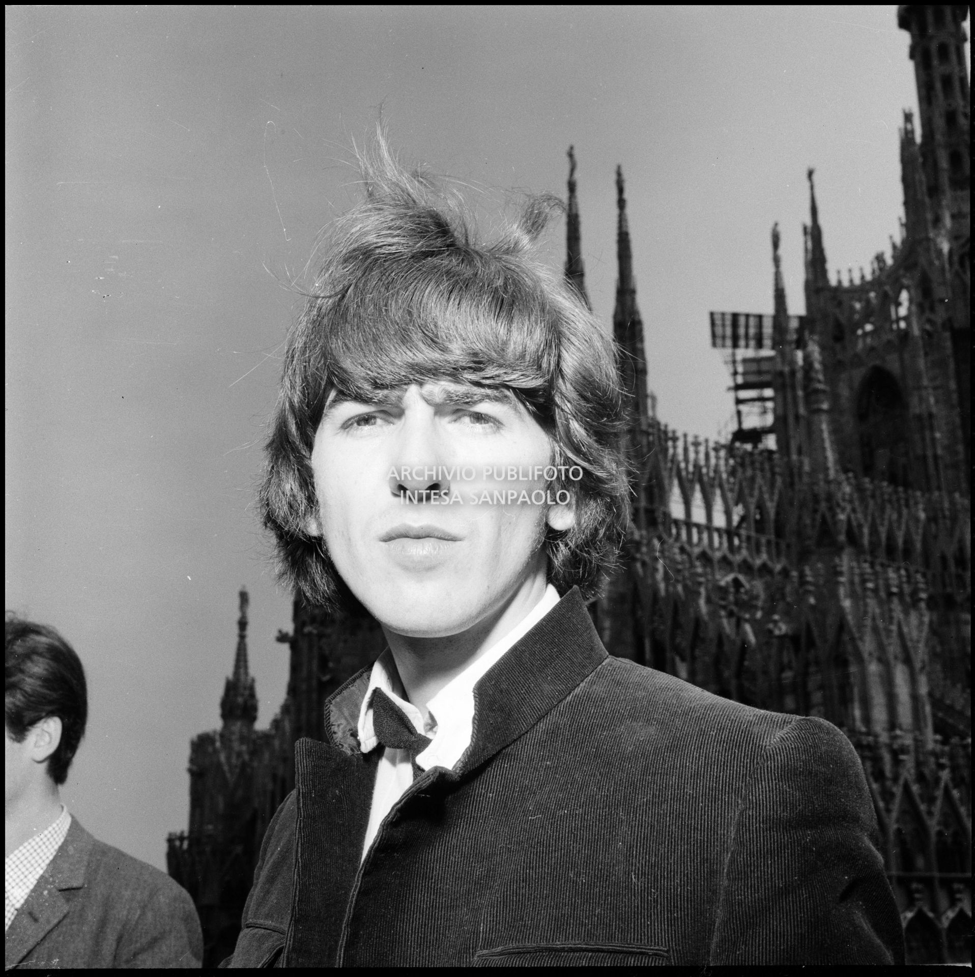 George Harrison ritratto sulla terrazza del Grand Hotel Duomo a Milano; sullo sfondo le guglie della cattedrale