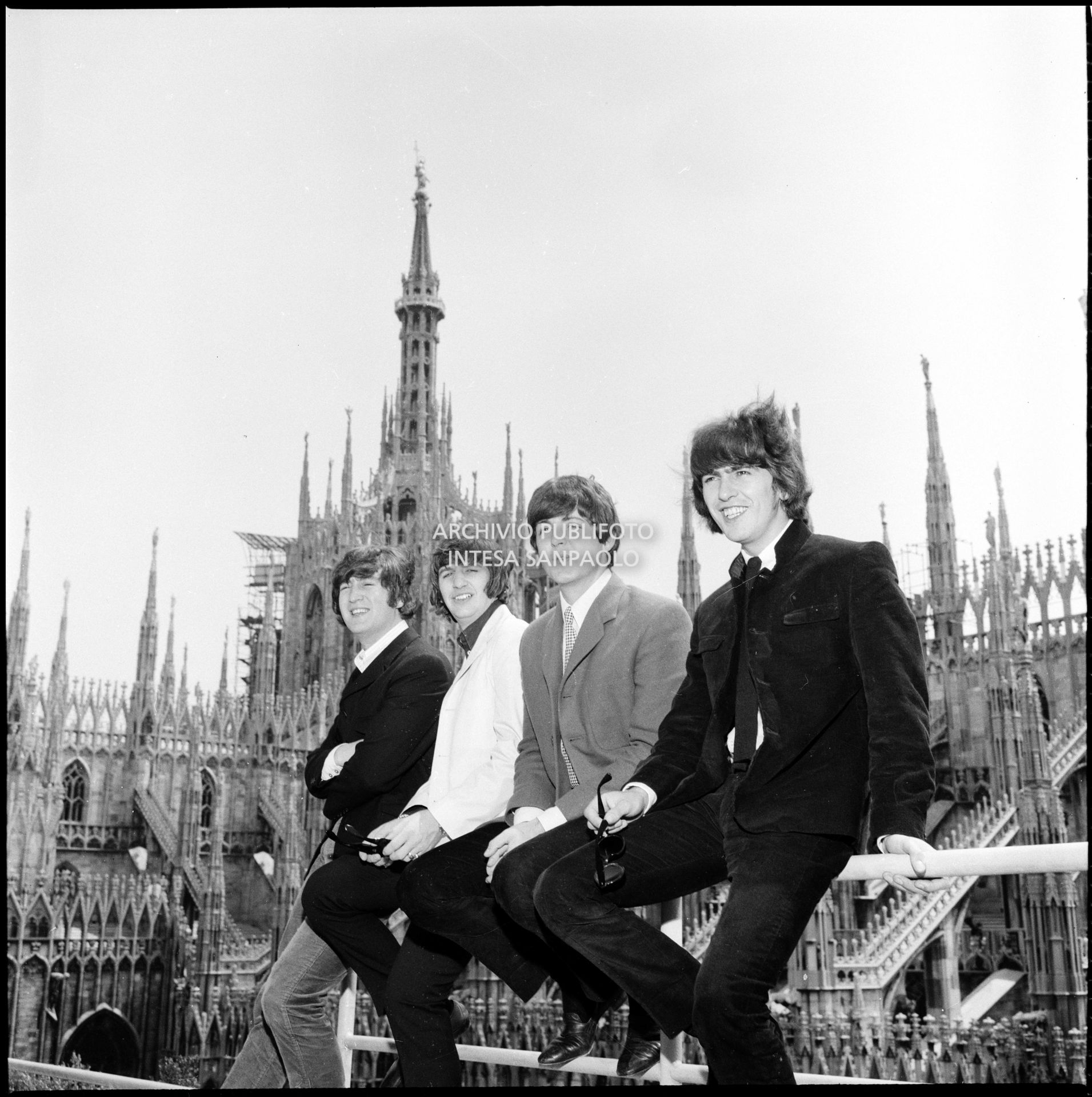 I Beatles ritratti sulla terrazza del Grand Hotel Duomo a Milano; sullo sfondo le guglie della cattedrale
