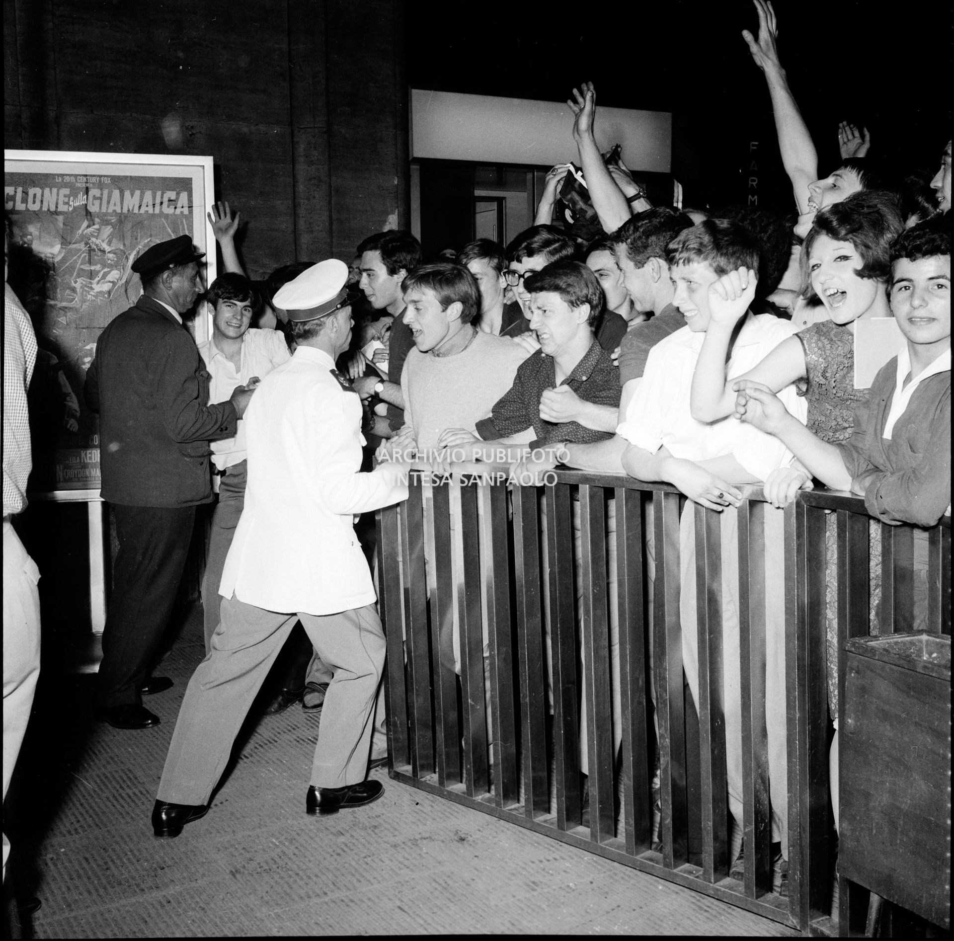 Poliziotti contengono l'entusiasmo dei fan dei Beatles in attesa dell'arrivo della band inglese alla Stazione Centrale di Milano