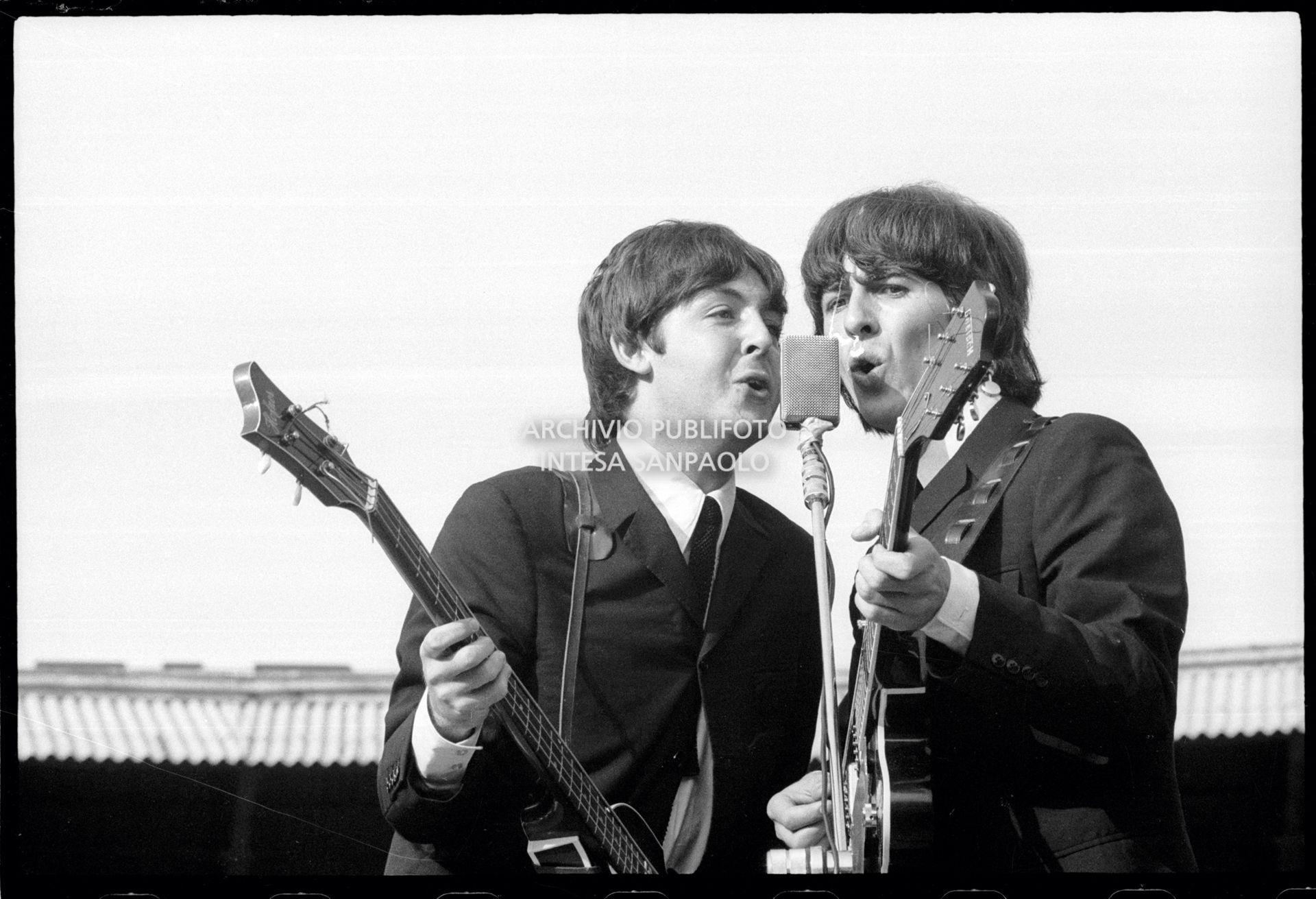 I Beatles in concerto al Vigorelli di Milano: Paul McCartney e George Harrison insieme al microfono con gli strumenti musicali, 24 june 1965, Cossu, Sergio, Pavone, Eugenio, Publifoto