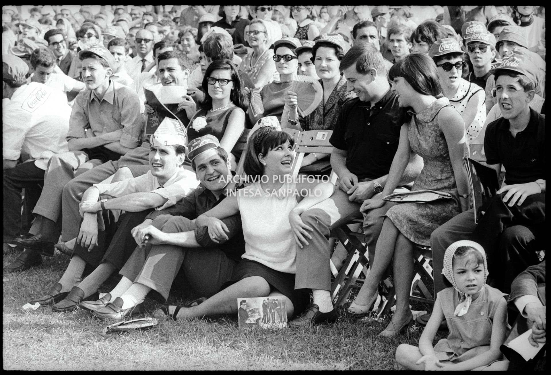 Claudia Mori con accanto Gino Santercole seduti a terra tra il pubblico al concerto pomeridiano dei Beatles al Vigorelli di Milano