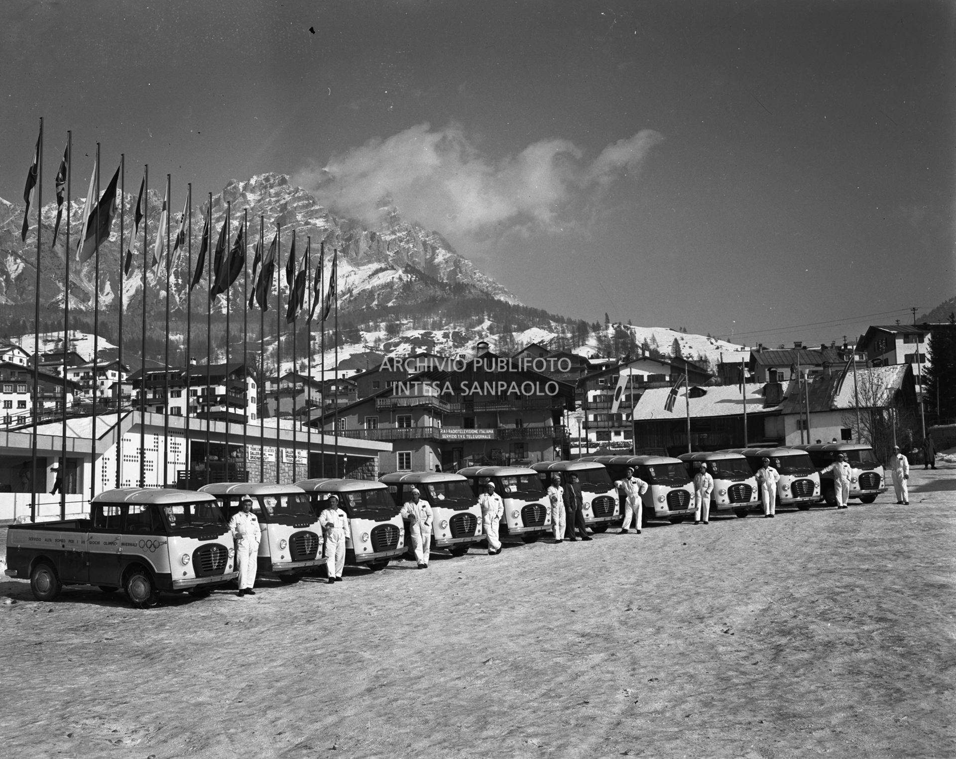 Furgoni Romeo della Alfa Romeo con autista, a disposizione dei partecipanti ai VII Giochi olimpici invernali, schierati davanti allo Stadio del ghiaccio a Cortina d'Ampezzo