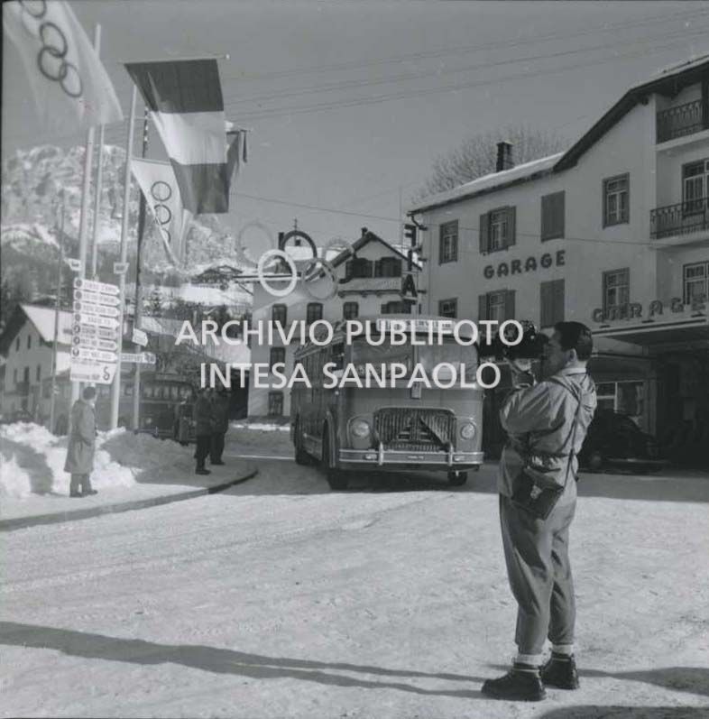 Un operatore della Rai e un pullman Fiat, adibito al trasporto del personale in servizio per i VII Giochi olimpici invernali, in una strada a Cortina d'Ampezzo