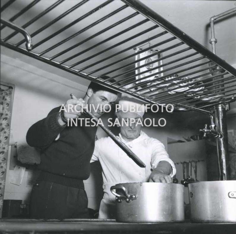 Lo sciatore alpino Toni Sailer nella cucina di un ristorante con il cuoco durante i VII Giochi olimpici invernali a Cortina d'Ampezzo