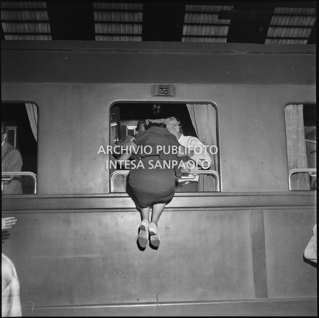 Una donna entra dal finestrino di un treno in partenza dalla Stazione Centrale di Milano, july 1954 - august 1954, Publifoto
