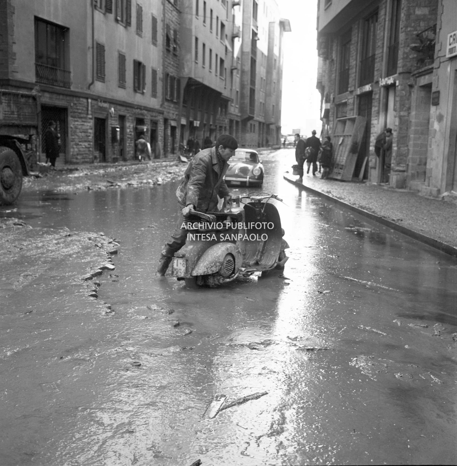 A man pushes a Vespa through the streets of Florence submerged in mud, after the flood