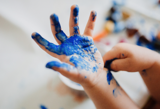 Image of a child’s hand covered in coloured tempera